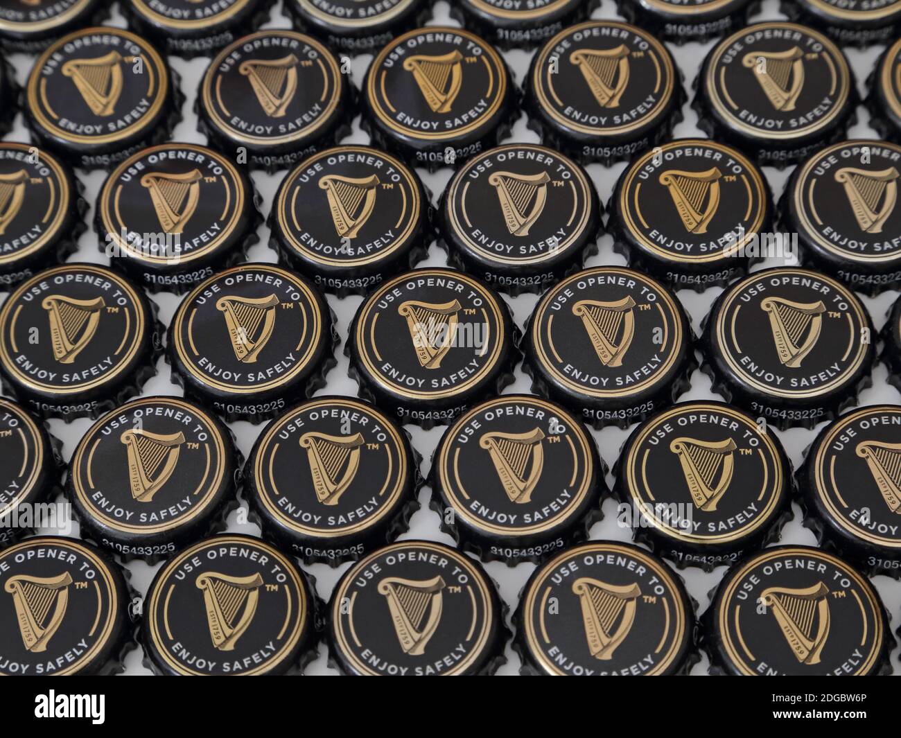 A collection of Guinness beer bottles caps are shown arranged in a flat display, viewed at an angle in the 2020s. For editorial uses only. Stock Photo