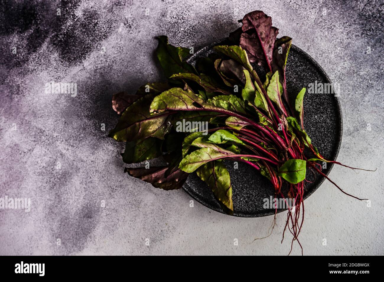Fresh beetroot leaves on a black plate Stock Photo