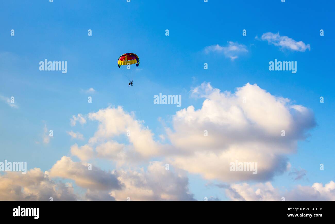 Multicolored parachute floats high in the sky among the clouds in the