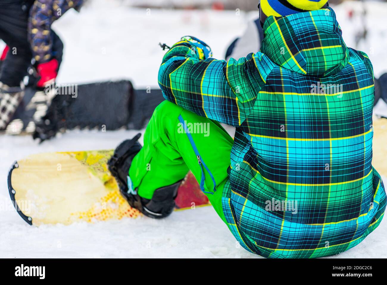 Rear view of snowboarder sitting on snow Stock Photo