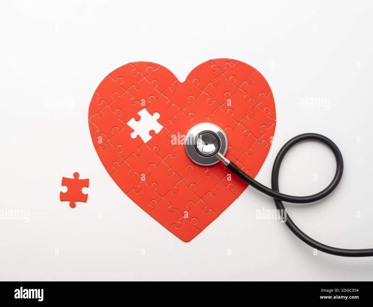 Stethoscope lying on heart shaped puzzle with missing piece Stock Photo