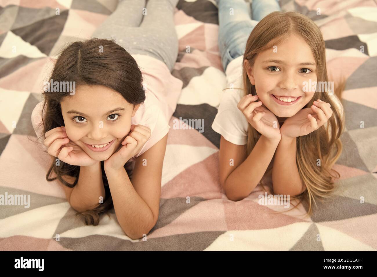 There are many reasons to be happy. Happy kids with cute smiles. Small children relax on bed. Enjoying happy childhood. Childhood happiness. Leisure and rest time. Naptime. Carefree and happy. Stock Photo