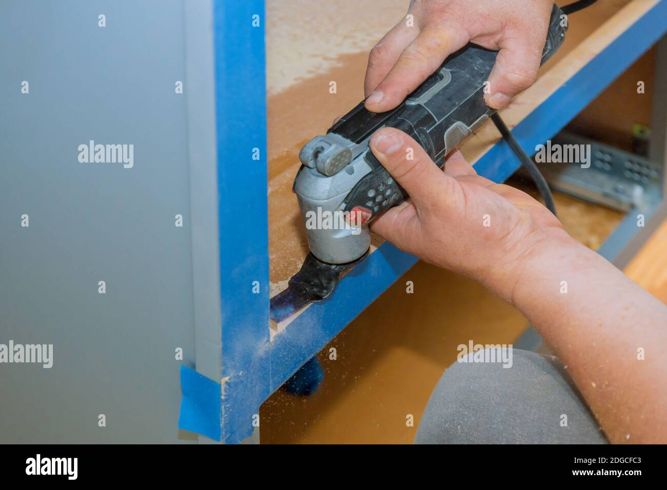 Contractor using oscillating multi functional cutting tool for handyman cut hole in kitchen furniture Stock Photo