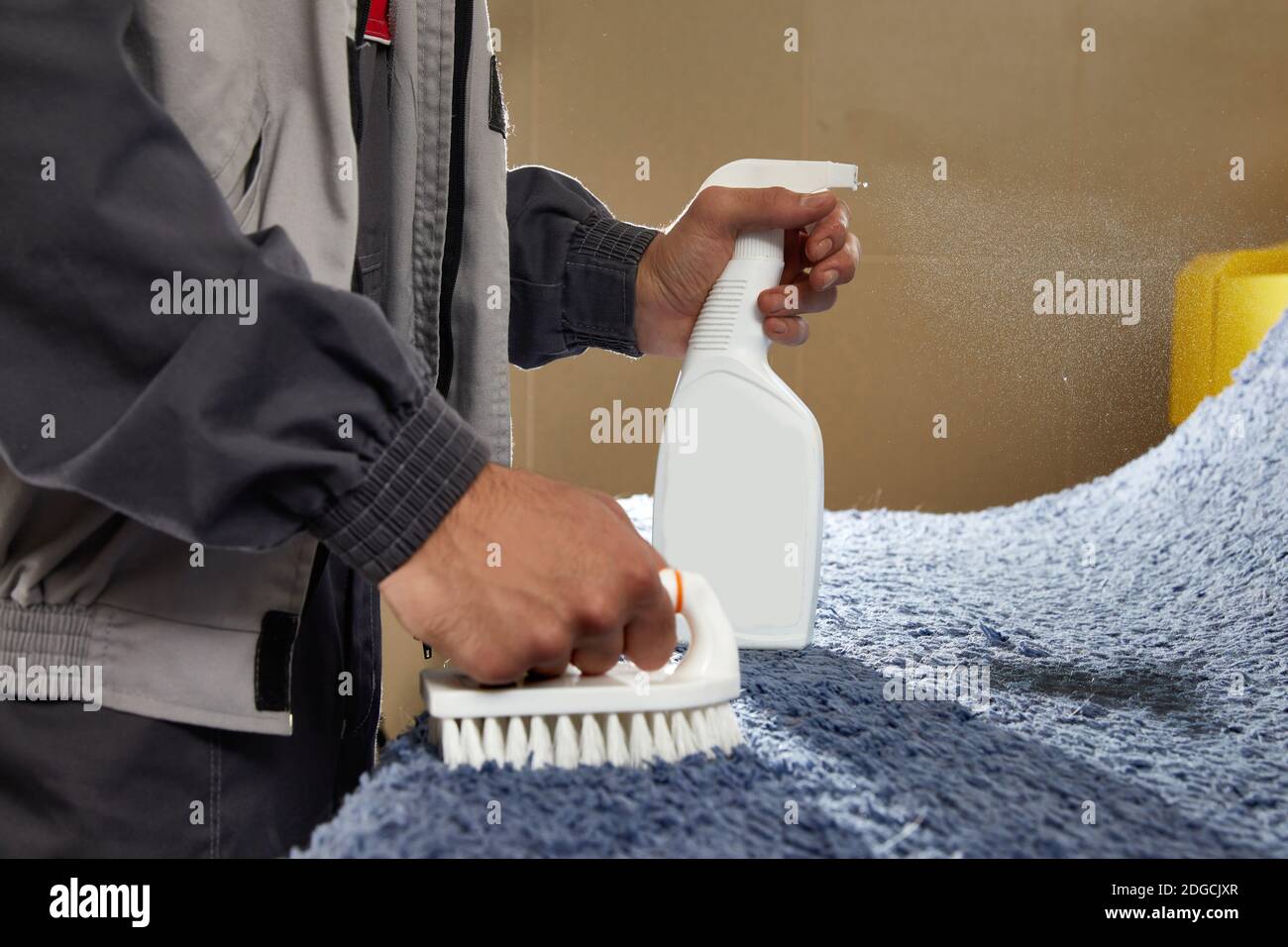 Man Spraying Detergent On Grey Carpet To Remove Stain in professional cleaning service  Stock Photo