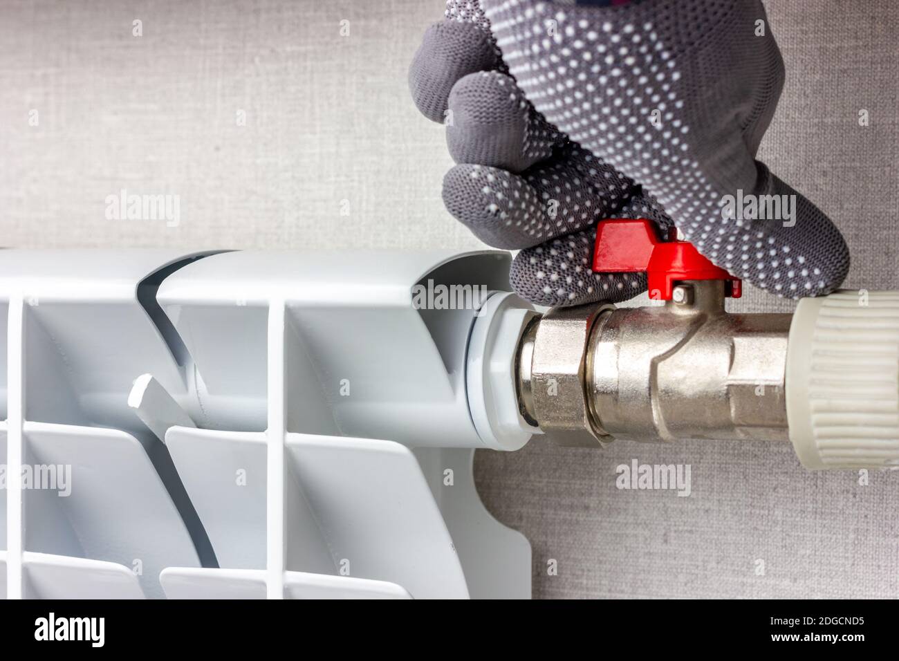 person turning off radiator thermostat with safety gloves