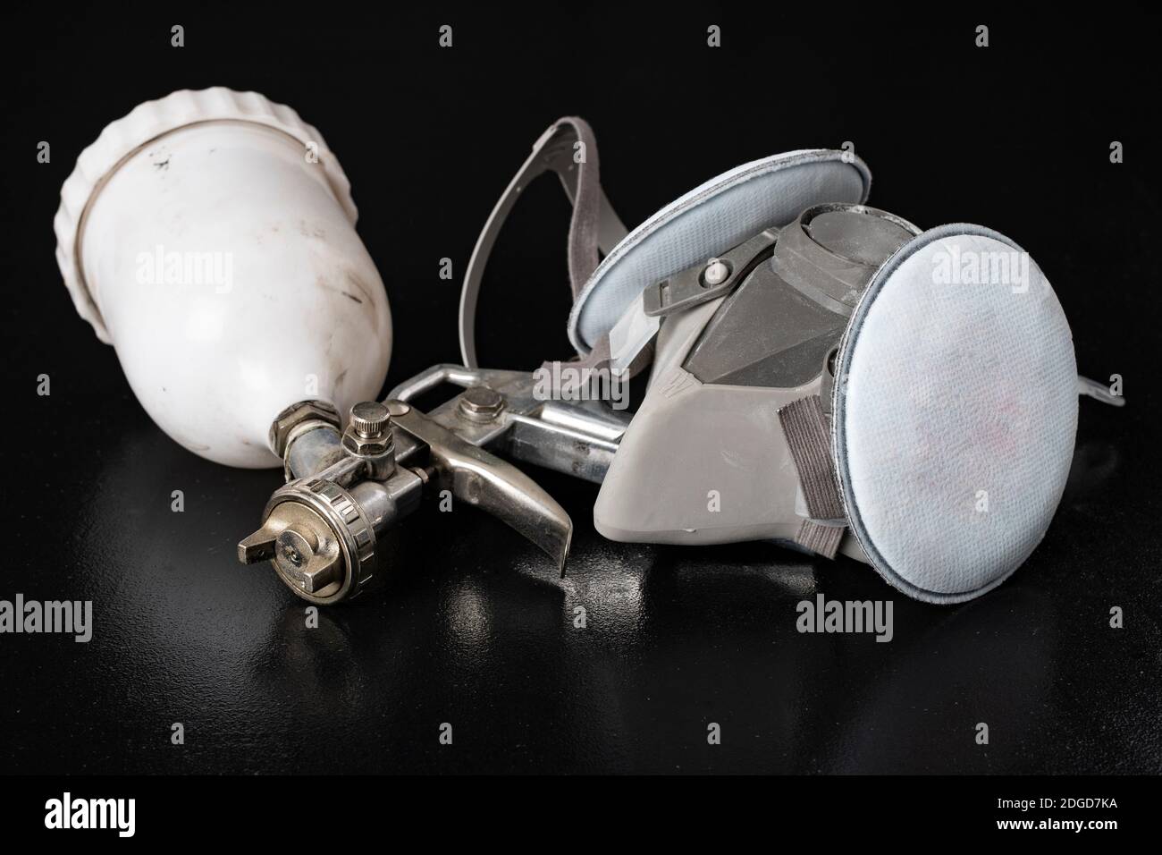 Metal spray gun for painting in a paint shop. Accessories for painting  works and protective clothing. Dark background Stock Photo - Alamy