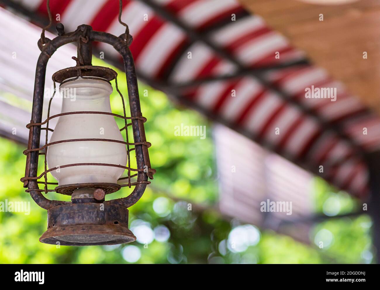 Old oil lamp with white glass with copy space on a blurry background textile roof polorussaya red wh Stock Photo