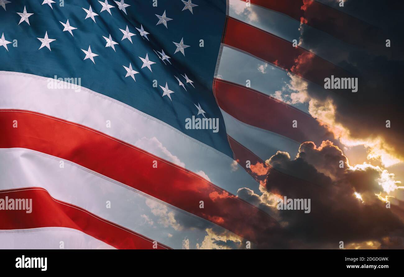 American flag waving in cloudy sky and bright sunrise over the horizon. Stock Photo
