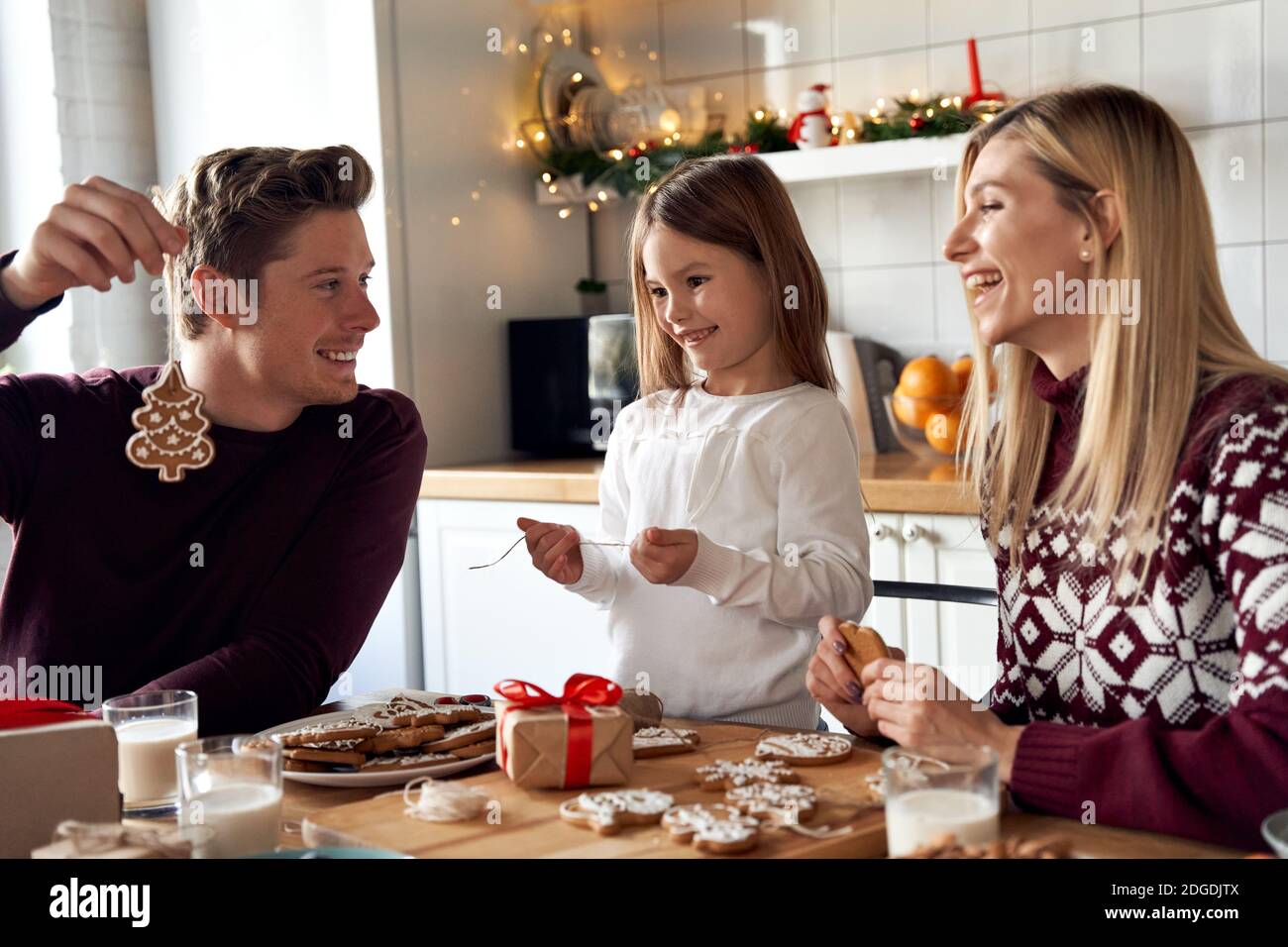 Happy family parents and kid making Christmas cookies decorations at home. Stock Photo
