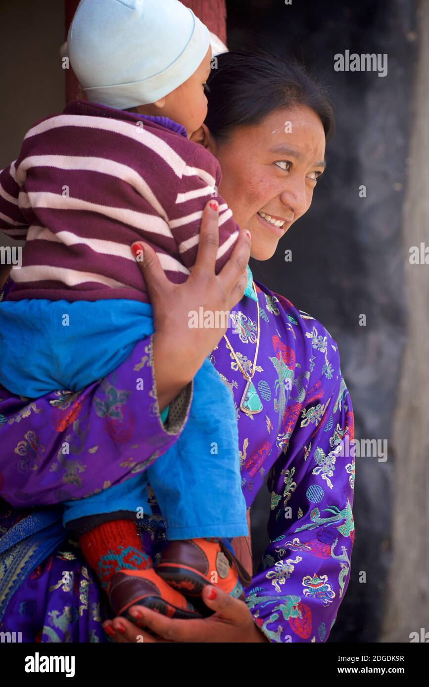 Ladakhi mother in festive dress carrying young child. Karsha Gustor festival, Karsha monastery, near Padum Zanskar Valley, Ladakh, Jammu and Kashmir, northern India Stock Photo
