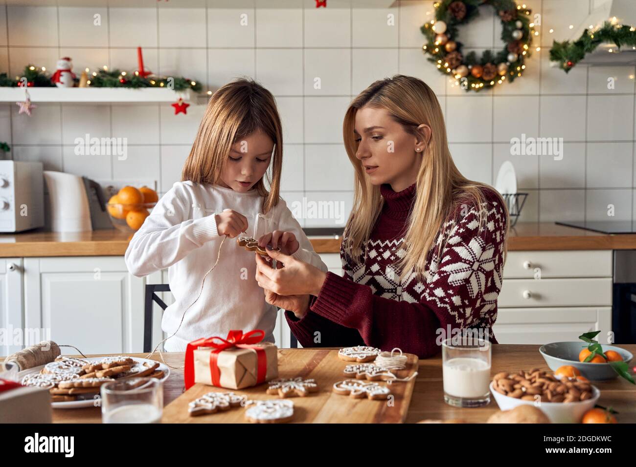 Mom helping kid daughter making Christmas cookies decorations at home. Stock Photo