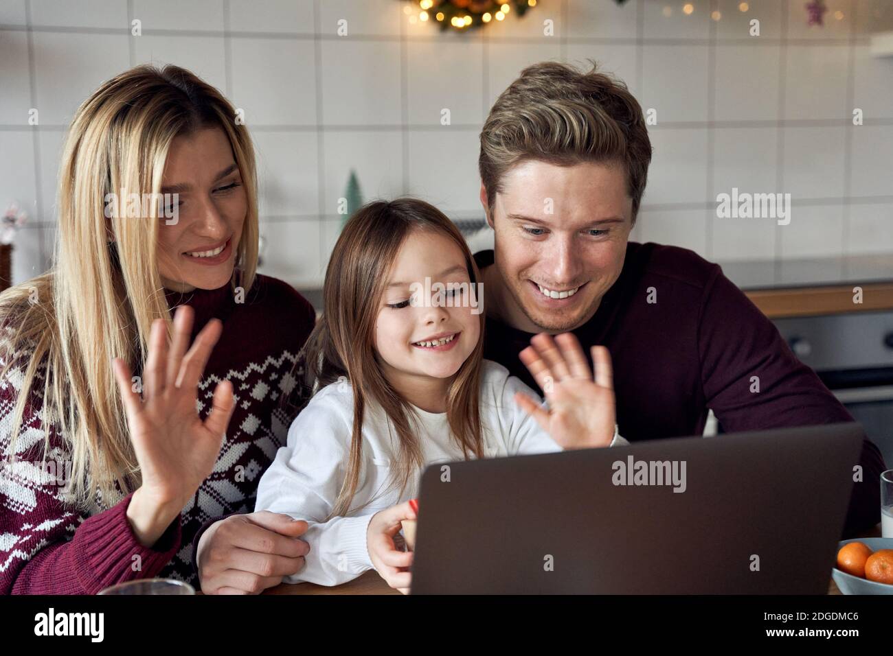 Happy family with child daughter using laptop having virtual party on videocall. Stock Photo