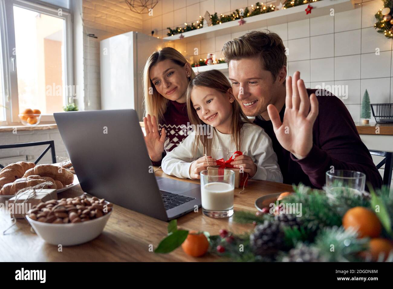 Happy family with kid daughter using laptop having virtual party on video call. Stock Photo