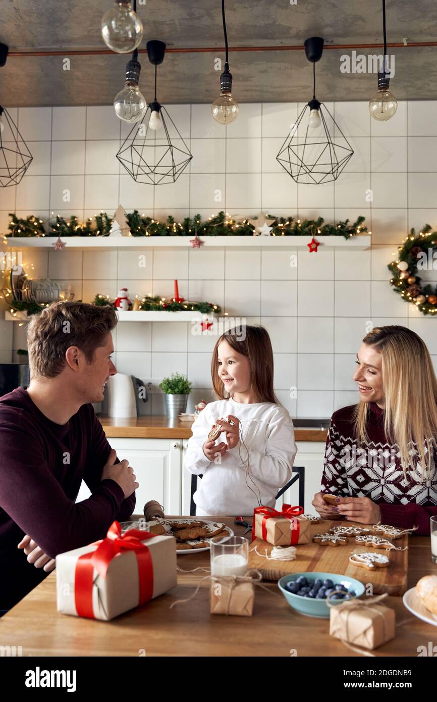 Young happy parents and kid daughter making Christmas cookies decorations. Stock Photo