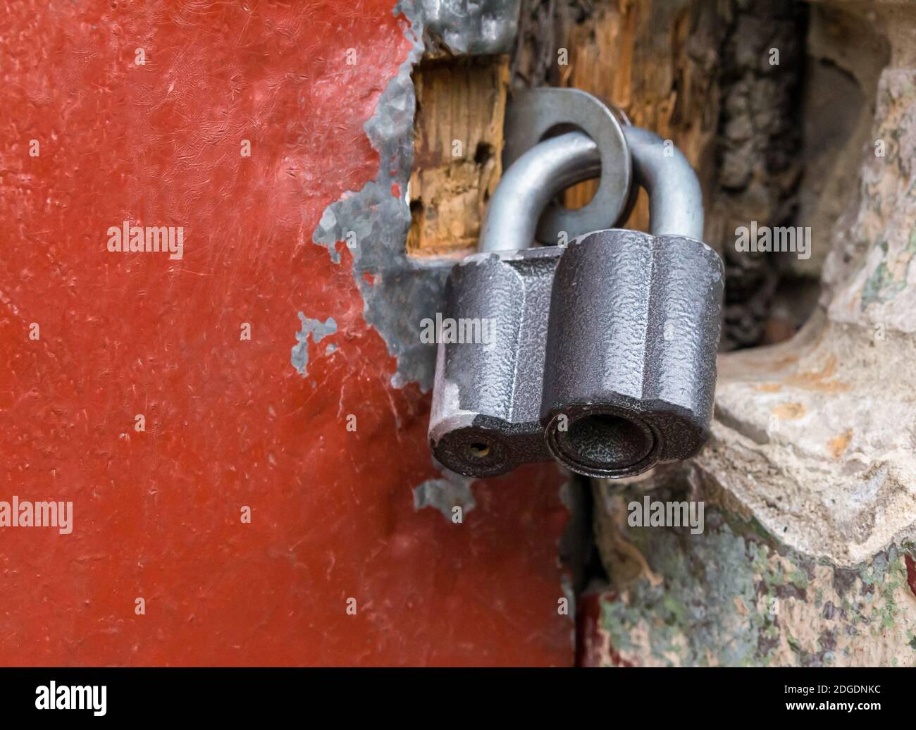 Wooden door bound with iron of red color is closed with a large padlock close-up Stock Photo