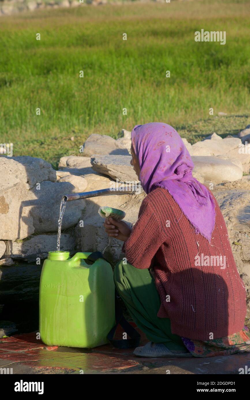 Woman collecting water from a standpipe. Pibiting village, Padum, Zanskar Valley, Ladakh, Jammu and Kashmir, northern India. Stock Photo