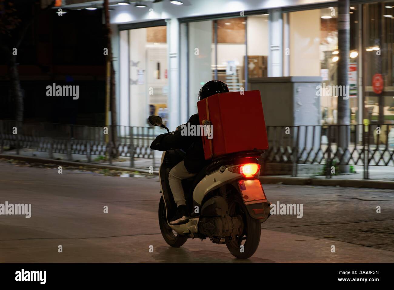 Delivery courier on unbranded motorbike speeding on city road at night