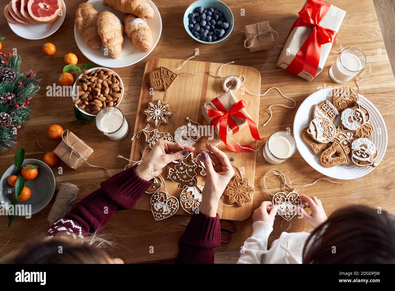 Top view of mom and kid daughter make Christmas cookies decorations over table. Stock Photo