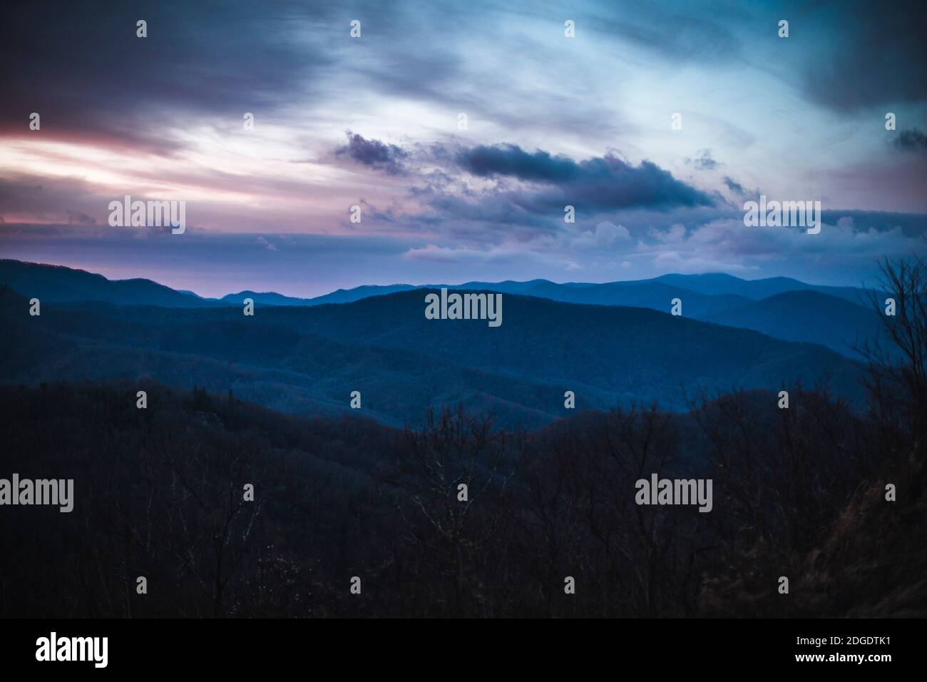 dramatic pink and purple clouds over smokey mountains at sunrise Stock Photo