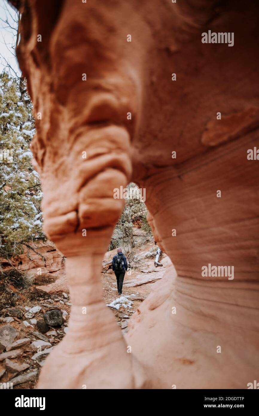 hiker walks down canyon near arch in Grand Staircase Monument, Utah Stock Photo