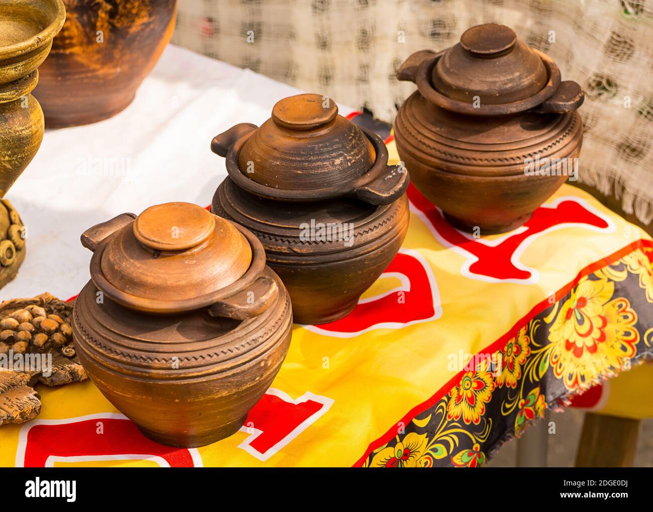Clay pots. Three vessels with a lid stand in a row, a rustic background. Natural products Stock Photo