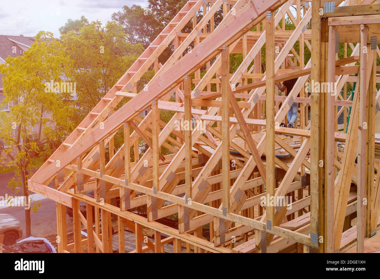 Panorama of condominium building with under construction wooden house with timber framing, truss, joist, beam close-up Stock Photo