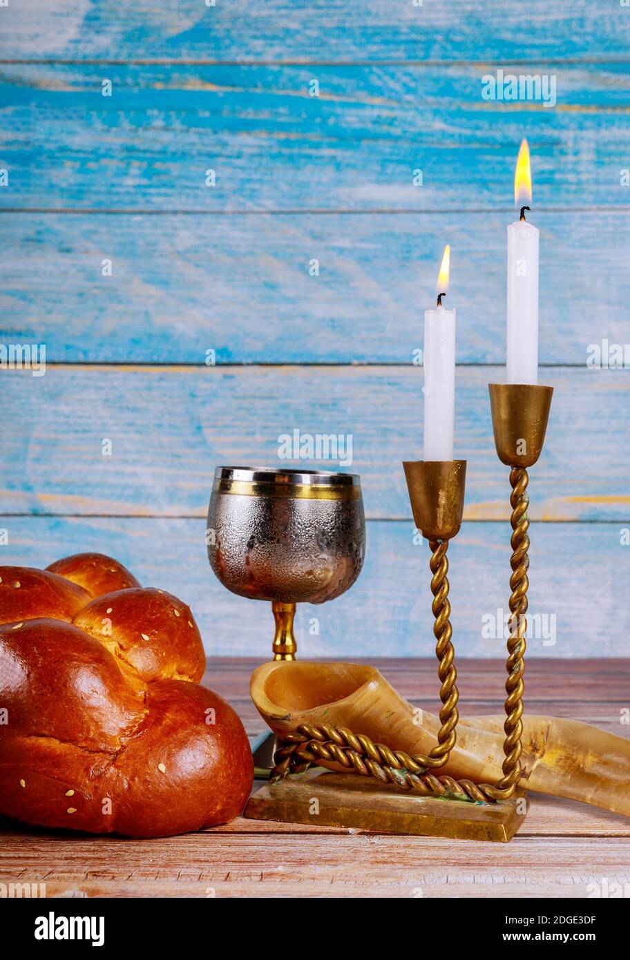 Shabbat eve table candles and cup of wine with covered challah bread