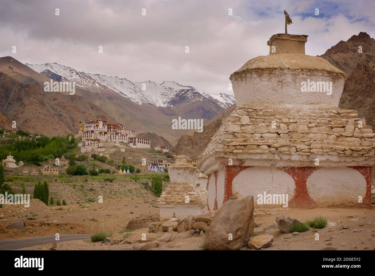 Likir monastery set amongst irrigated fields with mountain peaks beyond. Likir, Ladakh, Jammu and Kashmir, India Stock Photo