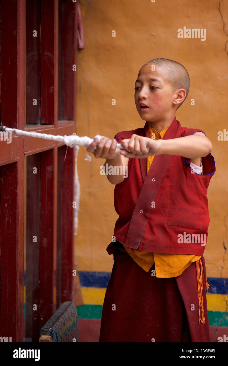 A young, novice monk undertaking chores. Cleaning monastery windows. Lamayuru monastery, Lamayouro, Ladakh, Jammu and Kashmir, India Stock Photo