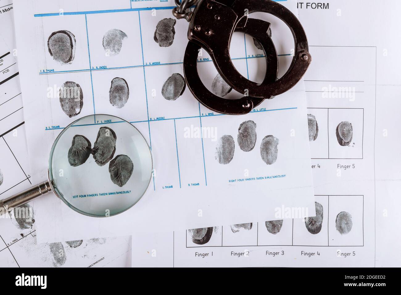 Police handcuffs and criminal fingerprints card, with magnifying glass, top view Stock Photo