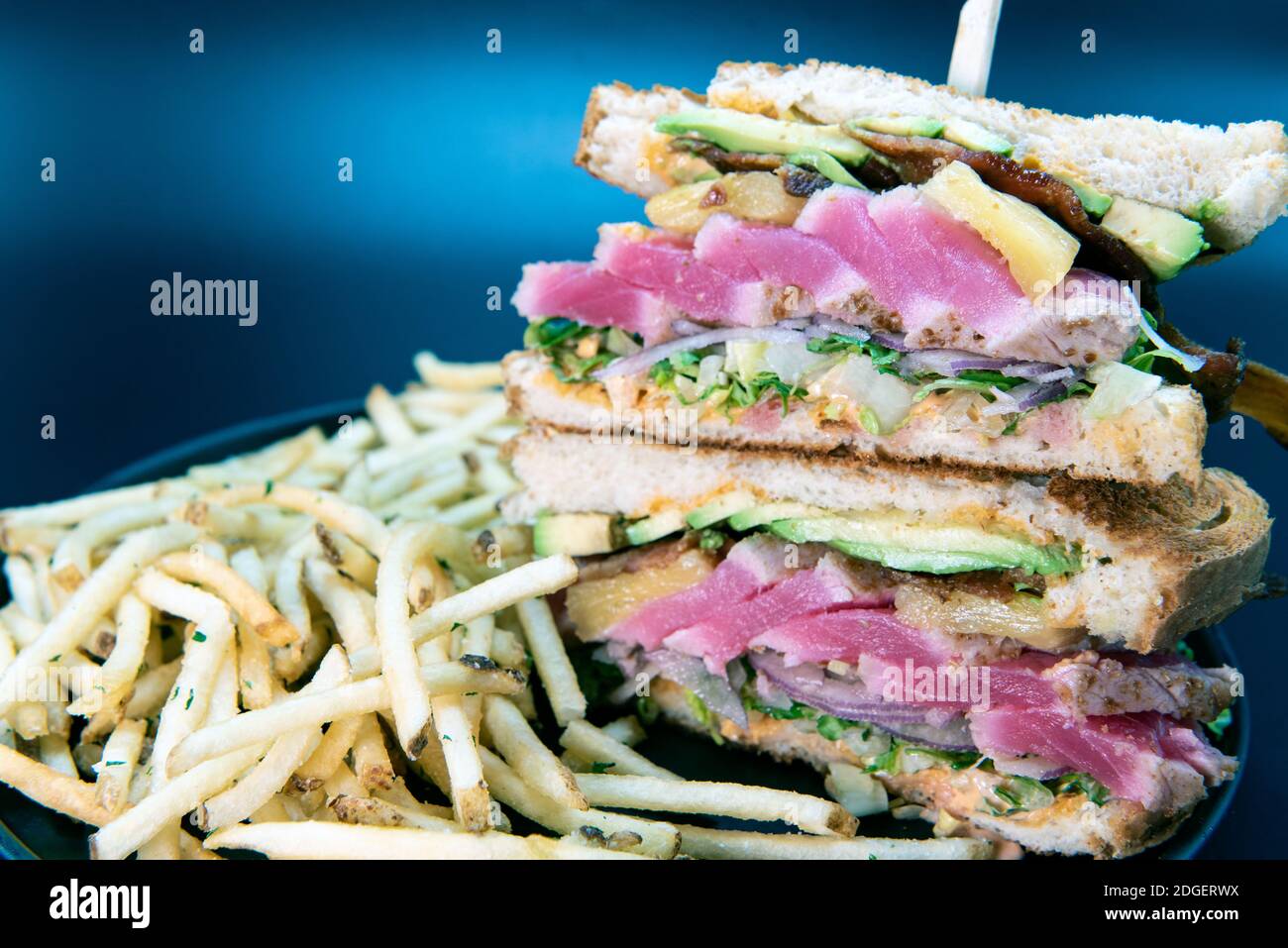 Tall order of Ahi tuna club sandwich and french fries loaded with all the toppings that the sour dough toast bread can hold Stock Photo