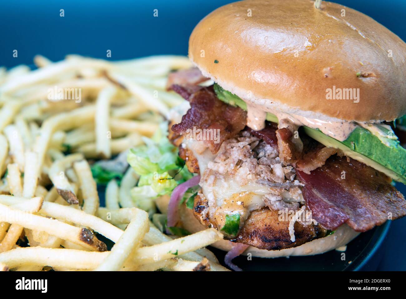 Tall order of avocado chicken sandwich and french fries loaded with all the toppings that the buns can hold Stock Photo
