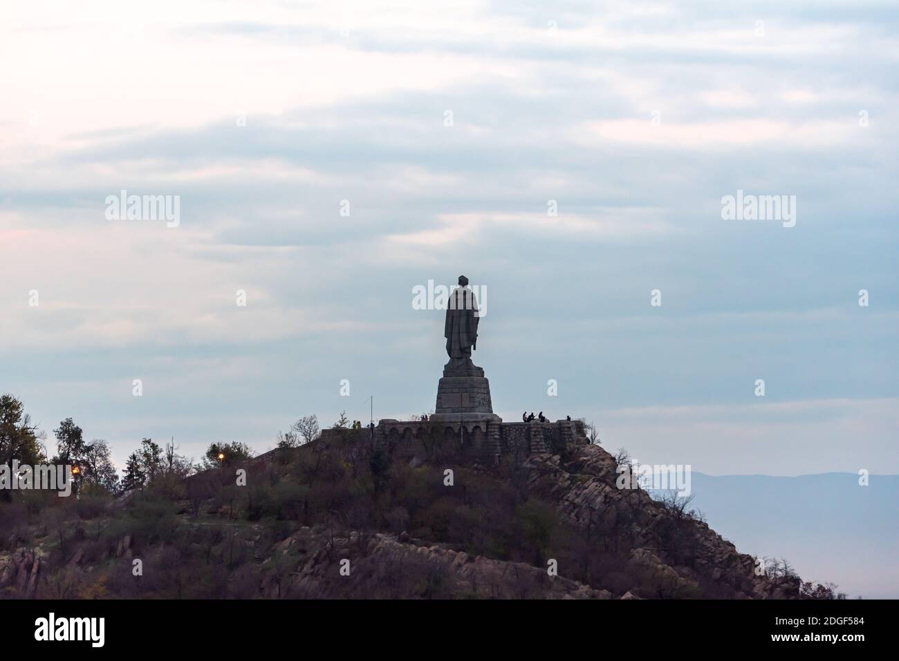 High statue on a hill looking over a massive Eastern European city of