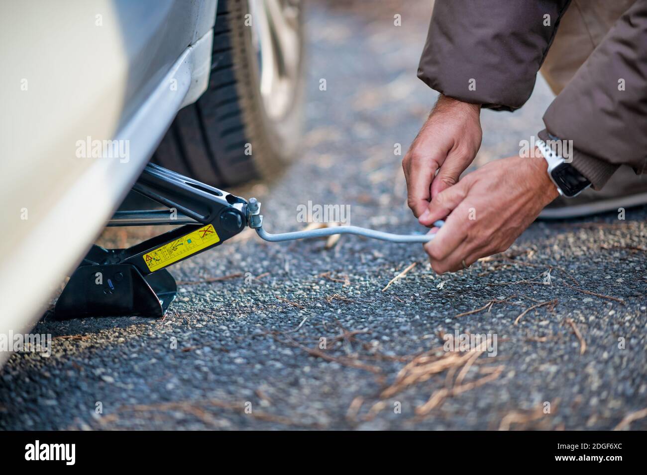 Man lifting the car on the jack for changing flat tire on the road Stock Photo