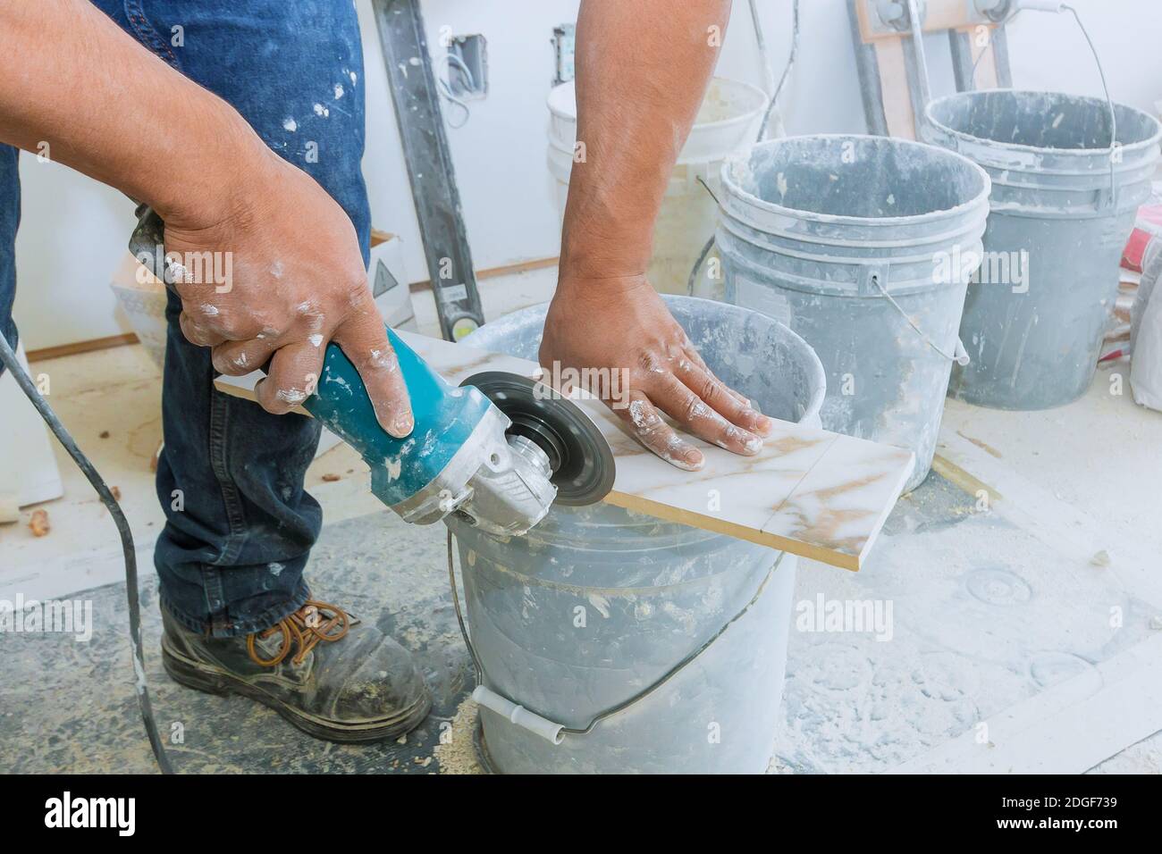 A construction worker cutting a tile using grinder Stock Photo