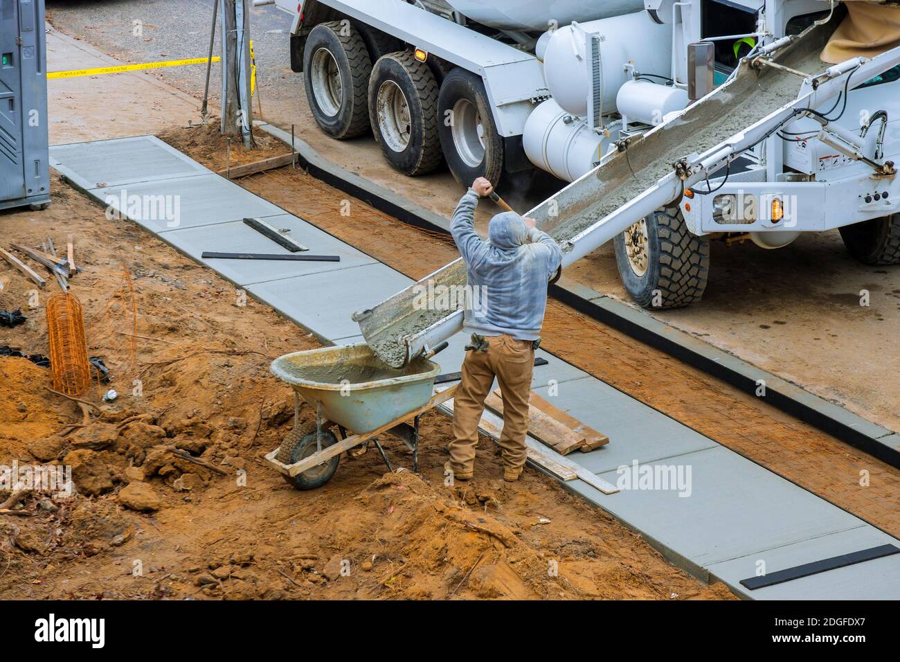 Construction worker pour cement for sidewalk in concrete works with mixer truck with wheelbarrow Stock Photo