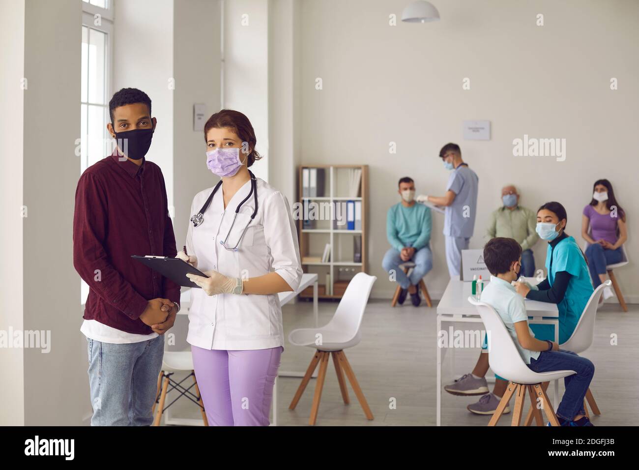 Nurse and patient in face masks standing in hospital office during