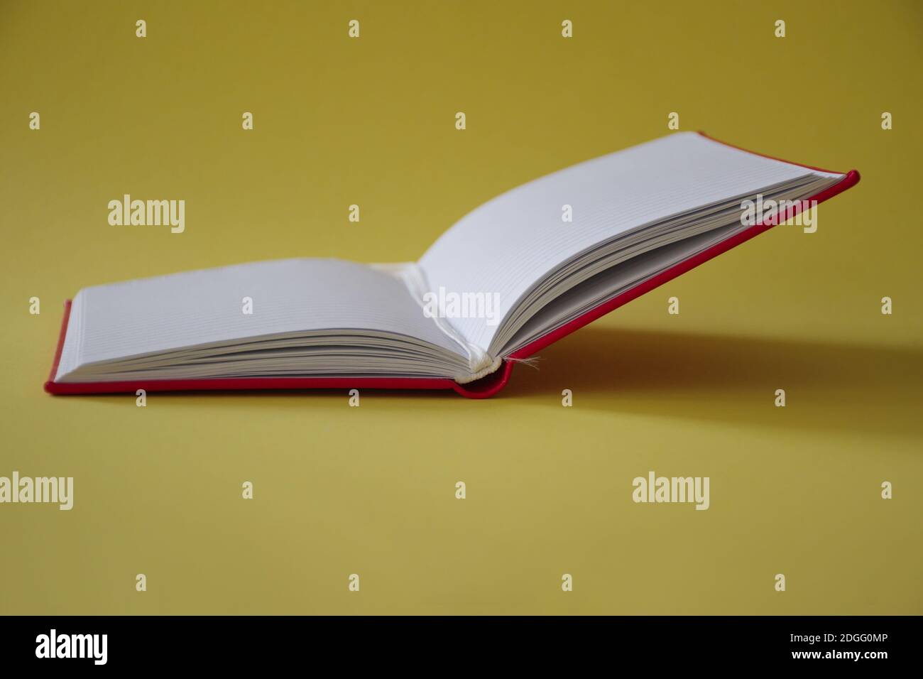 Open red notebook on yellow background Stock Photo