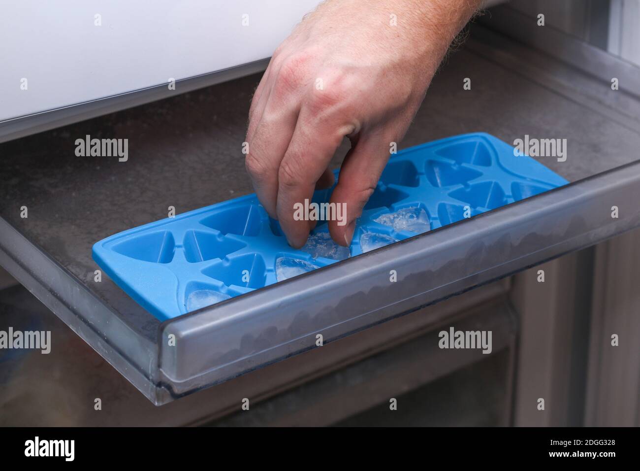 A man takes ice from a freezer tray to freeze low food in one layer. Stock Photo