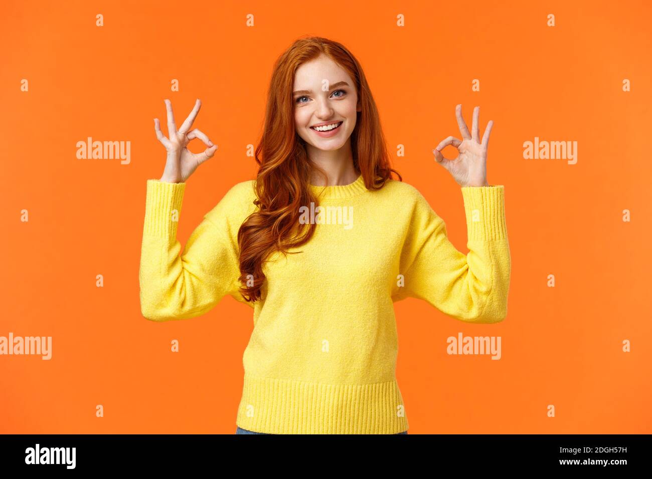 Perfect idea concept, acception. Good-looking redhead girl in yellow sweater, showing okay, good or approval sign smiling nod ag Stock Photo