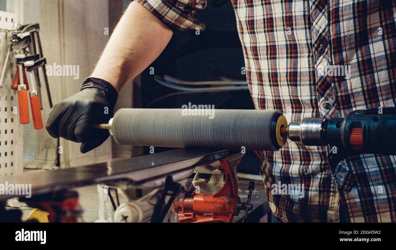 Base polishing, final ski polishing. In hands electric brush rotor. rotary brush use ski repair master at ski equipment store. h Stock Photo
