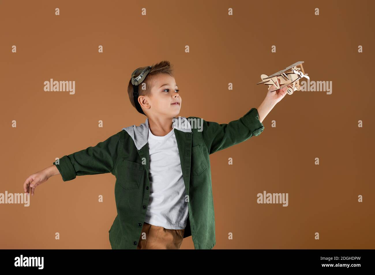 happy child boy playing with wooden toy airplane on studio background ...