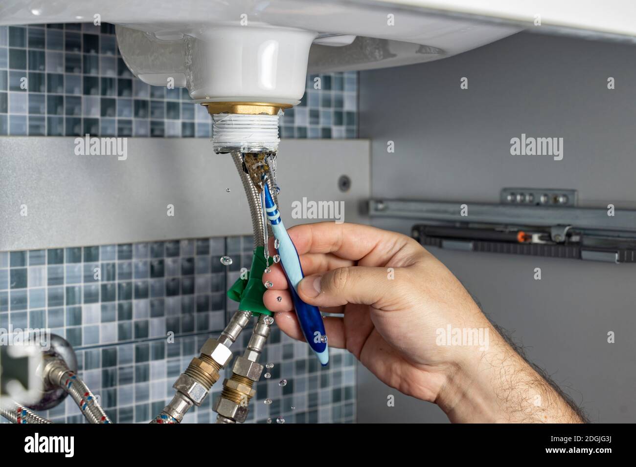 the plumber is cleaning the siphon of the washbasin in the bathroom