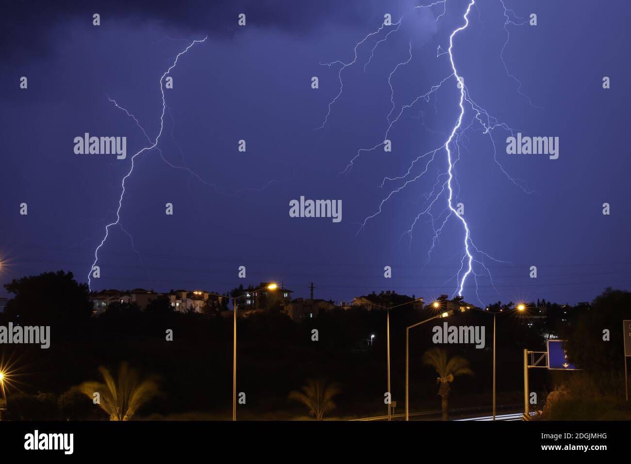 Lightning thunder storm over city in blue night with city lights Stock Photo
