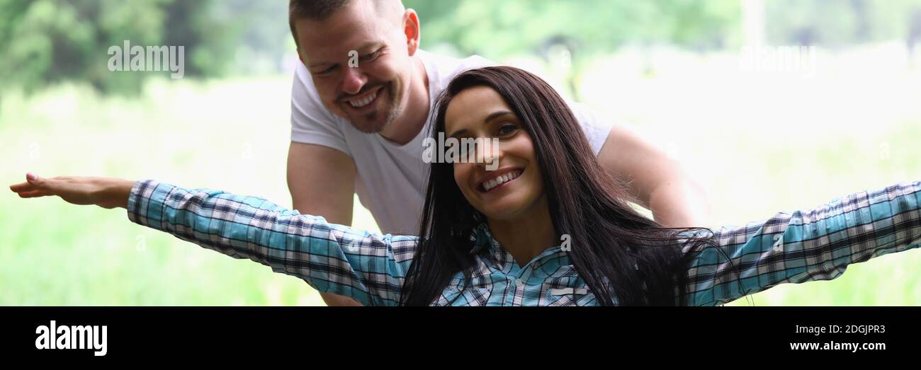 Woman is sitting in wheelchair smiling with her arms spread out man is rolling. Stock Photo