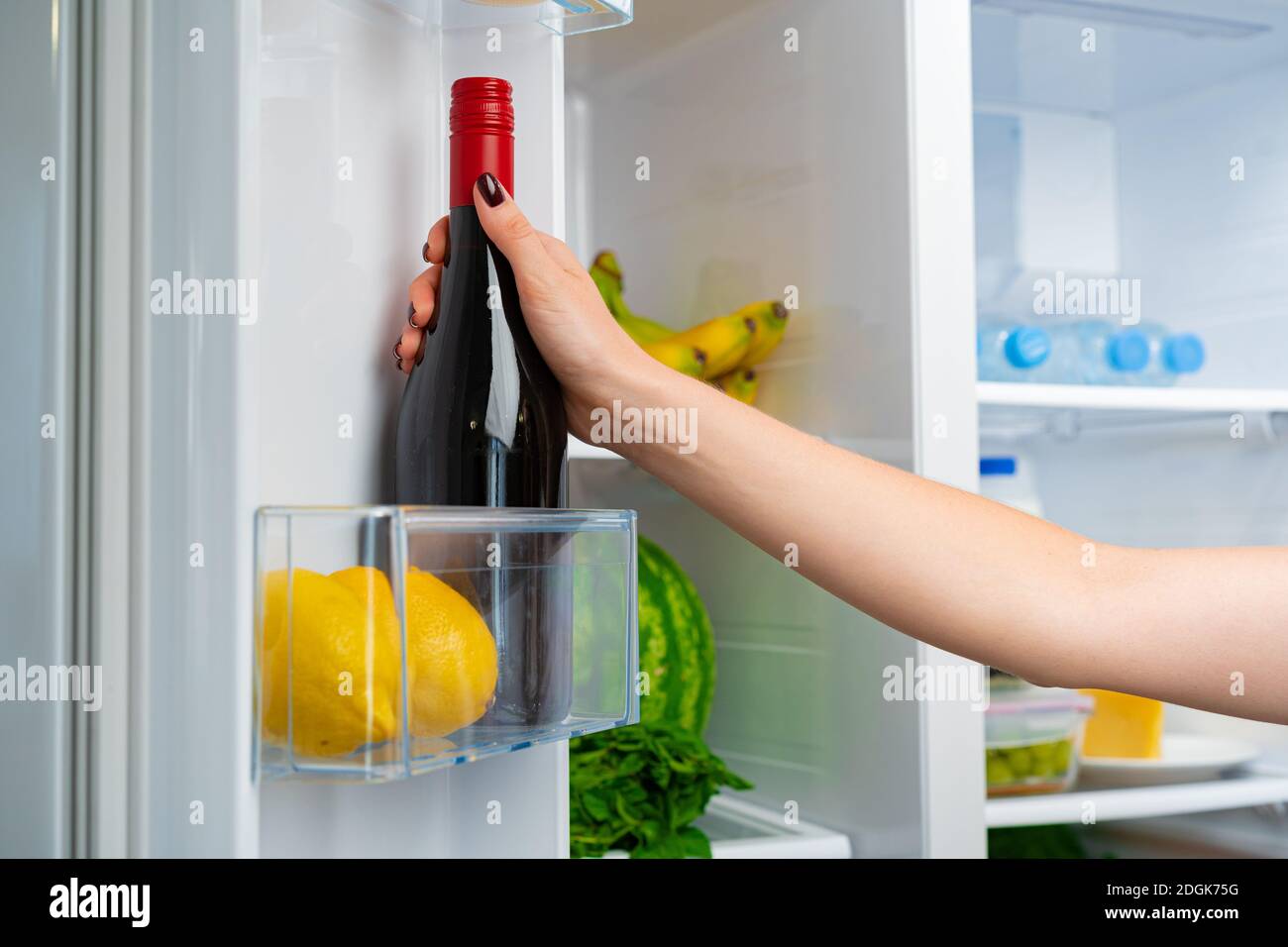 Female hand taking bottle of wine from a fridge Stock Photo Alamy