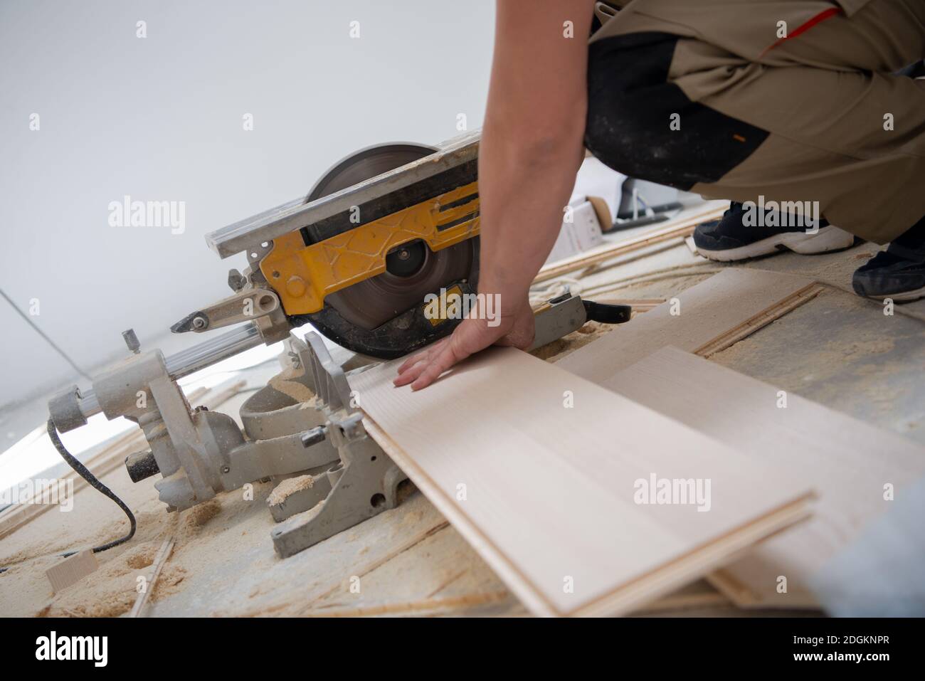 Man cutting laminate floor plank with electrical circular saw Stock