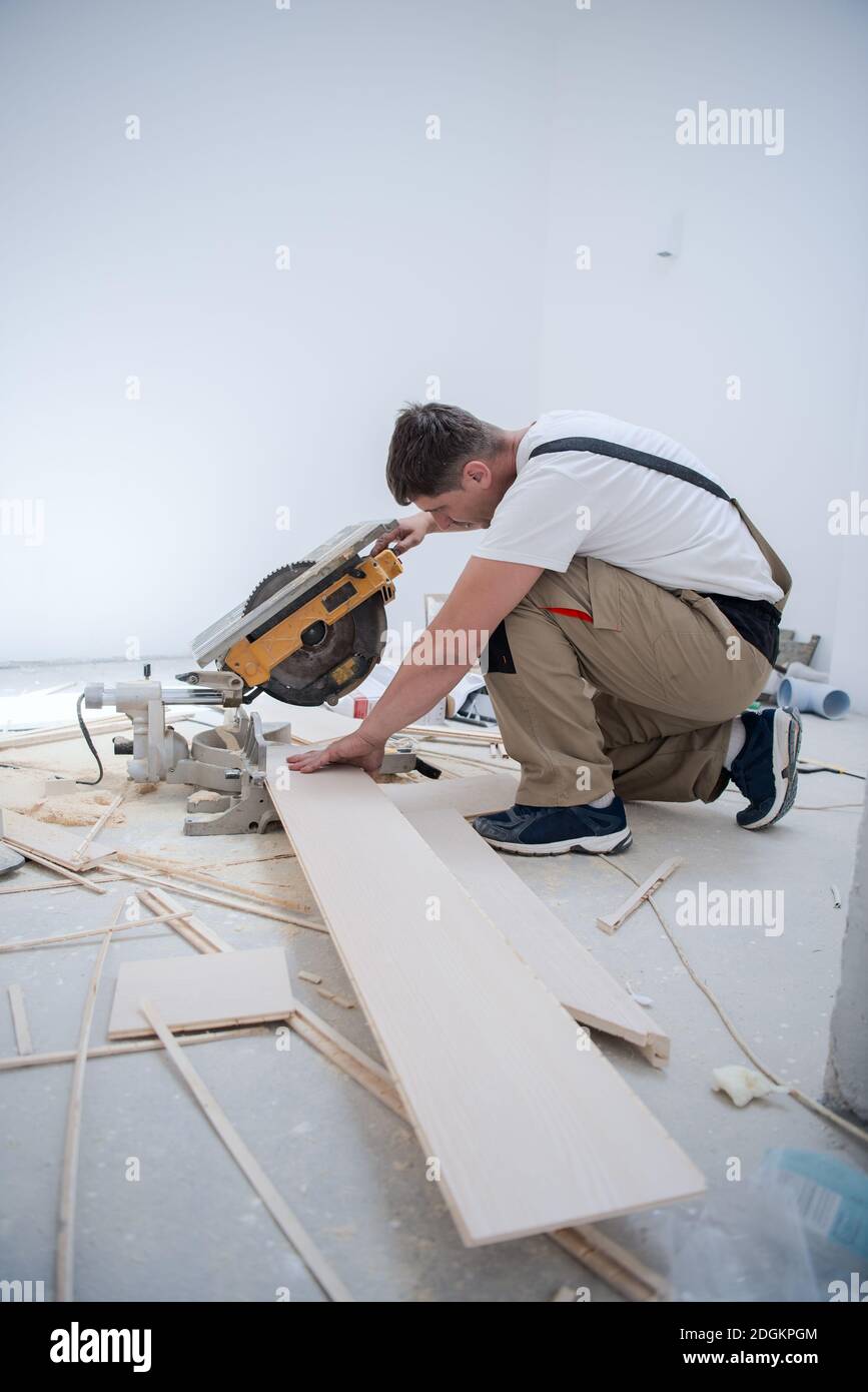 Man cutting laminate floor plank with electrical circular saw Stock