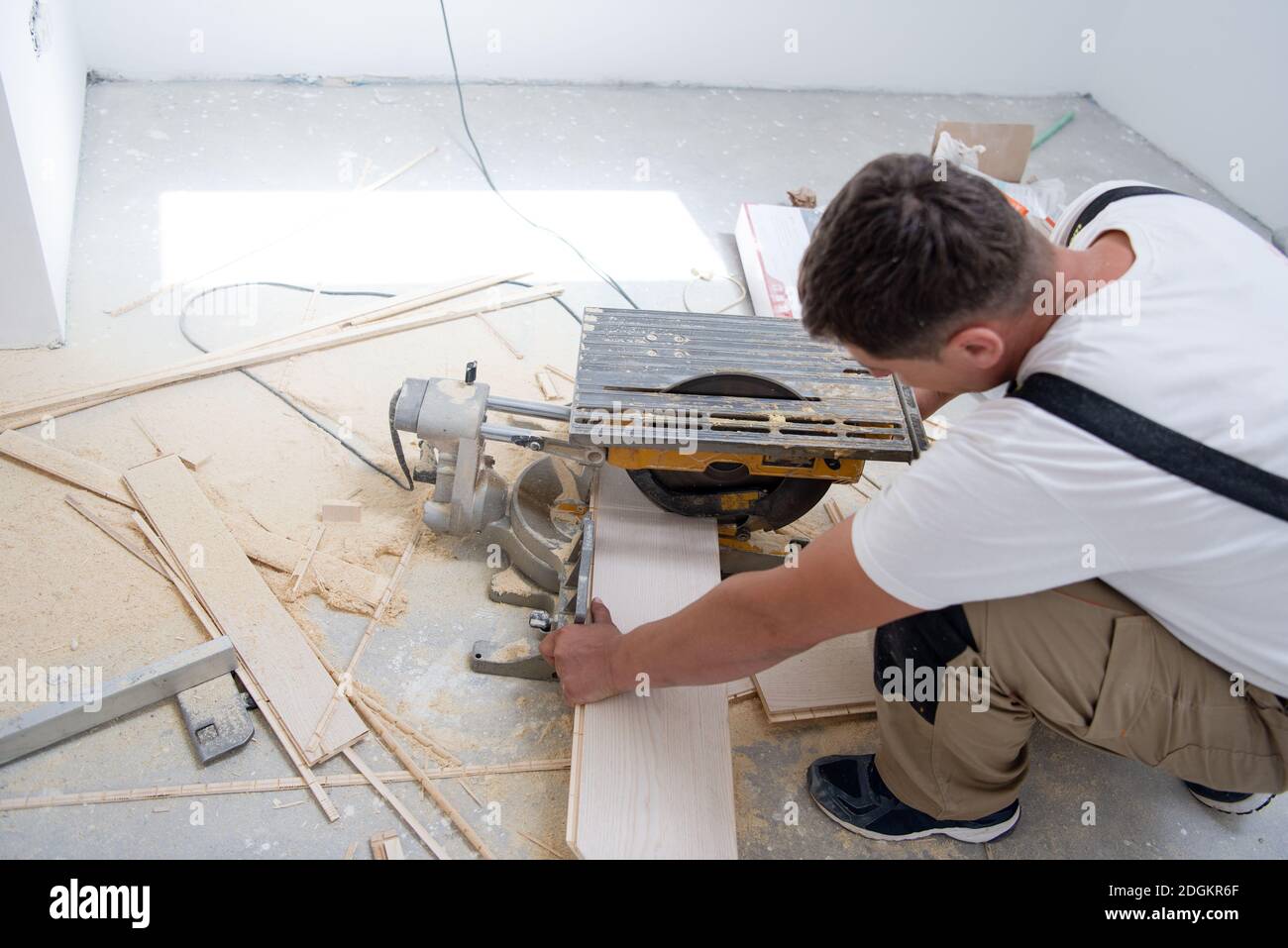 Man cutting laminate floor plank with electrical circular saw Stock