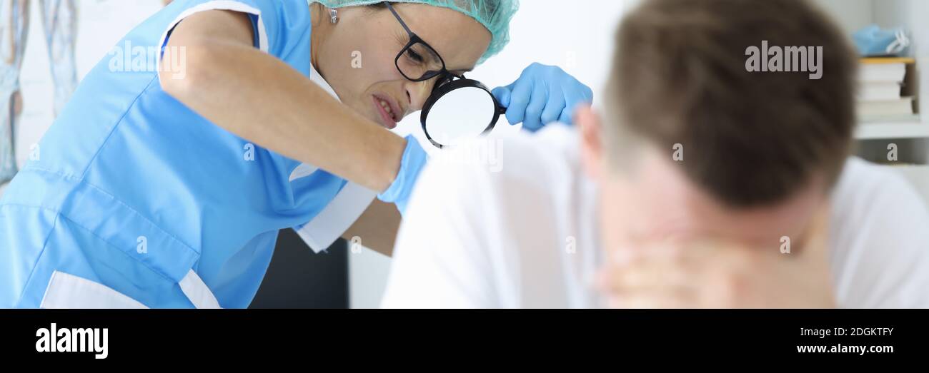 Practitioner doctor with magnifying glass in his hand examines rectum of man patient portrait Stock Photo